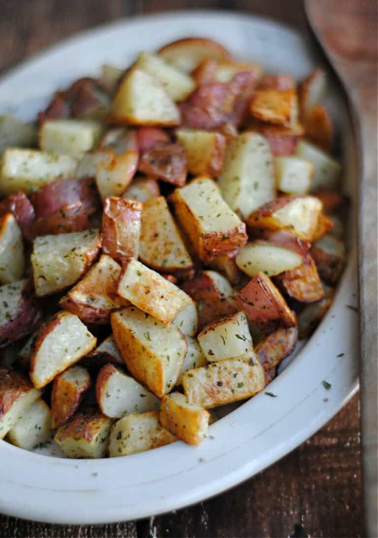 a white dish with Oven Roasted Red Potatoes in it.