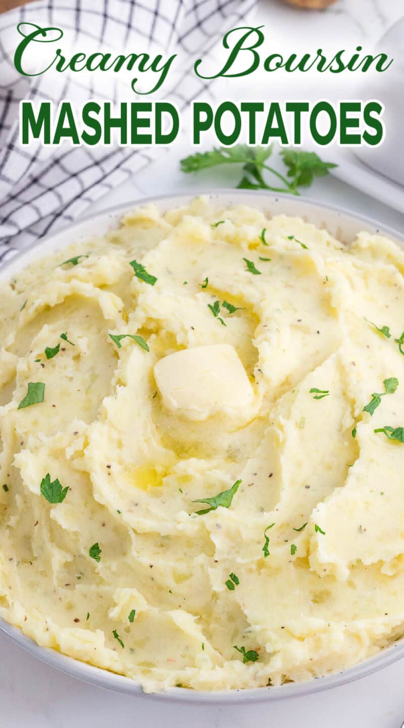 Boursin mashed potatoes with butter and chopped parsley on top in a bowl.