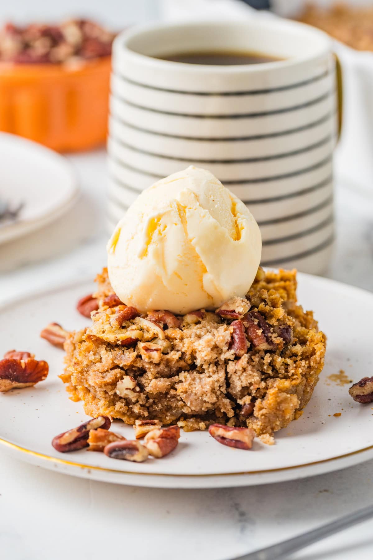 A piece of pumpkin dump cake on a plate with a scoop of ice cream on top.