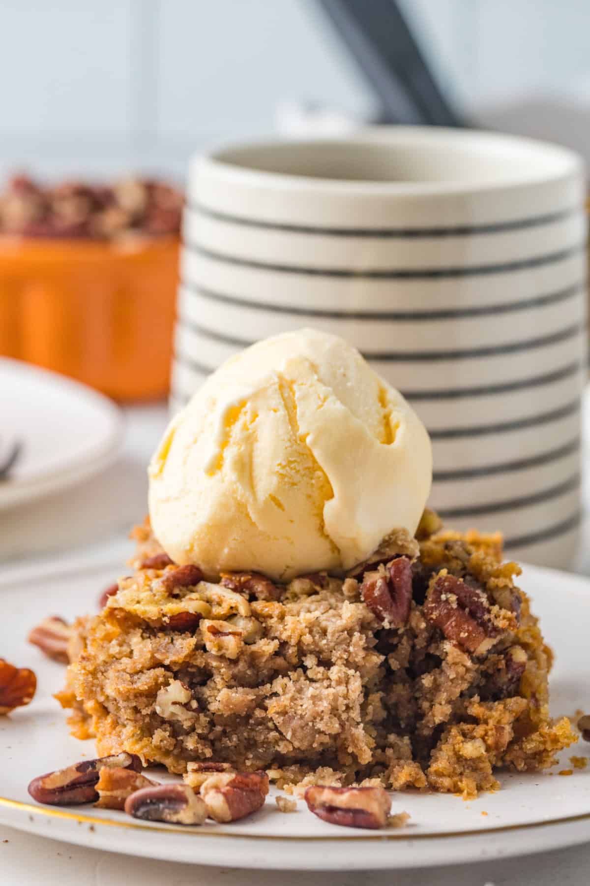 A piece of pumpkin dump cake on a plate with a scoop of ice cream on top.