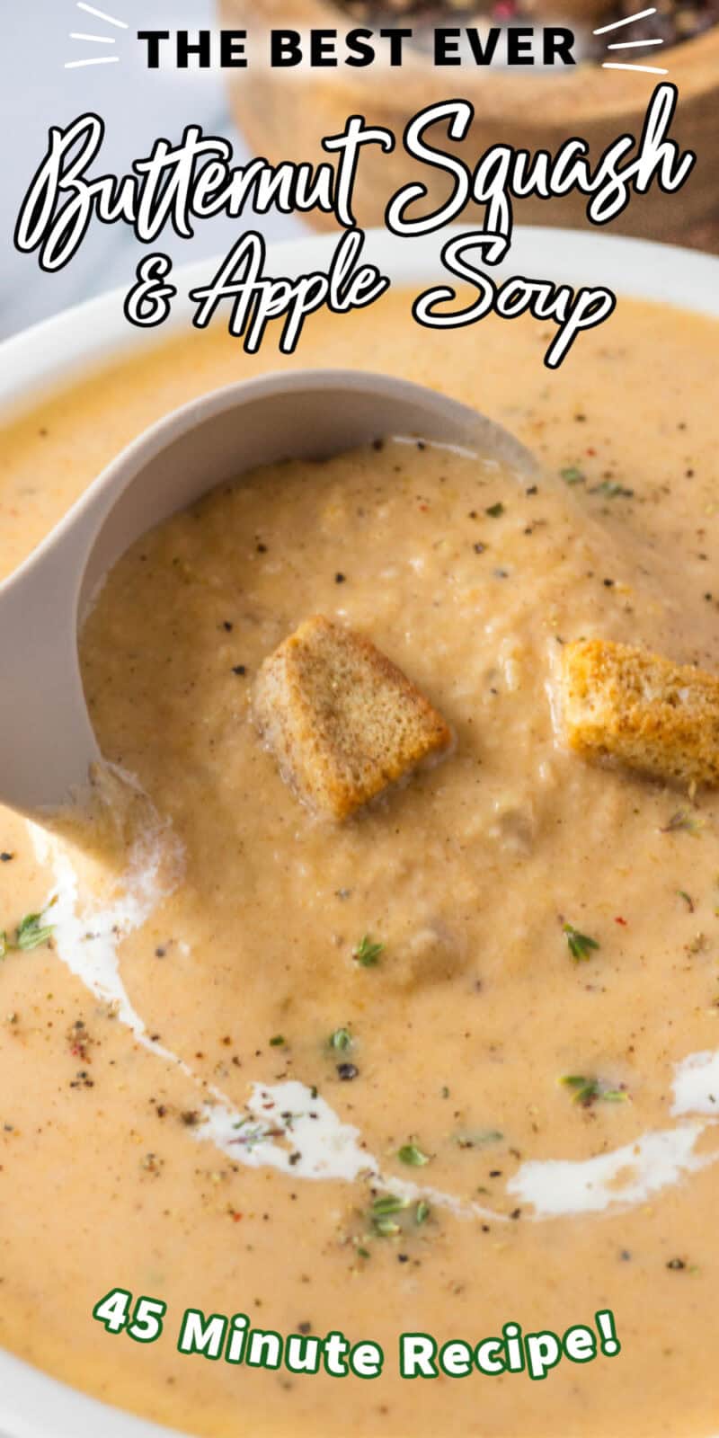 Creamy homemade Butternut Squash Soup with Apple in a white bowl with bread croutons, fresh herbs, and black pepper.