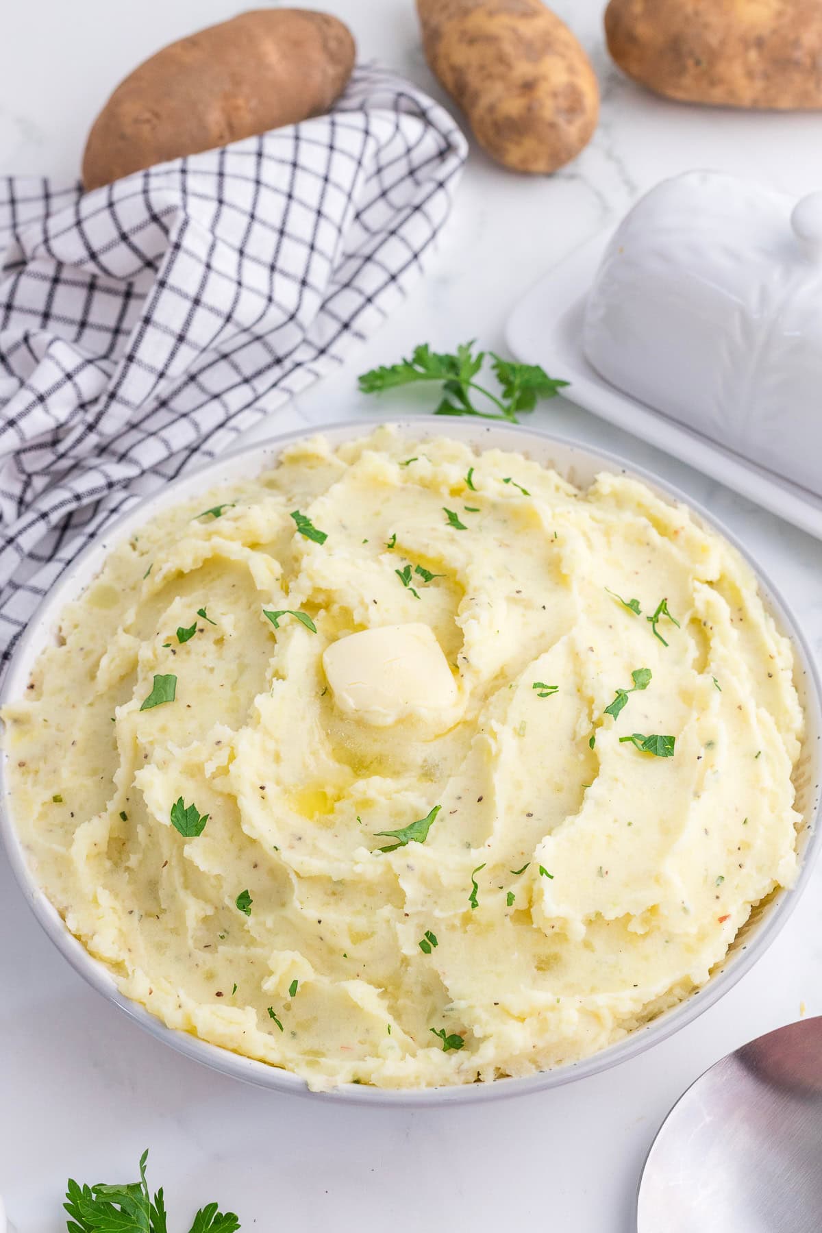 Boursin mashed potatoes with butter and chopped parsley on top in a bowl.