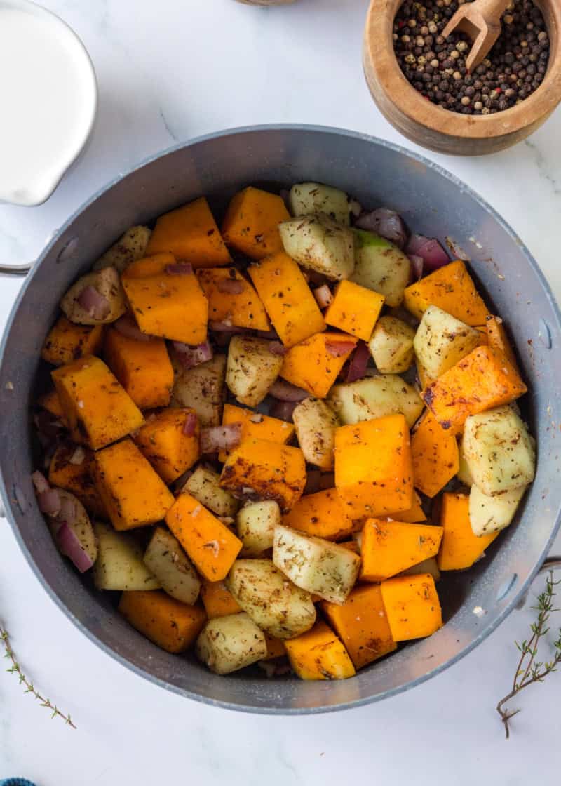 a pot of cubed butternut squash and apples with onions to make a soup.