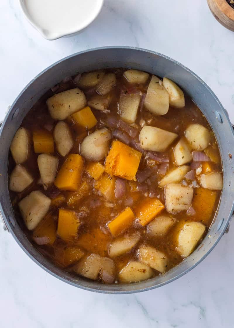 a pot with cooked cubes of butternut squash, apples and onions.