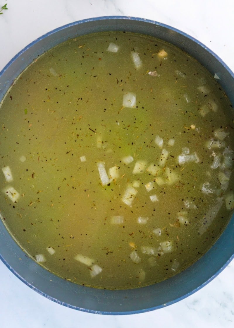 a pot of soup with broth and onions.