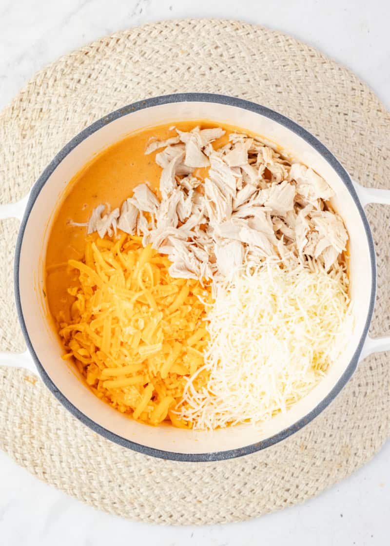 Shredded chicken and cheese in a melted cheese mixture in a pot.