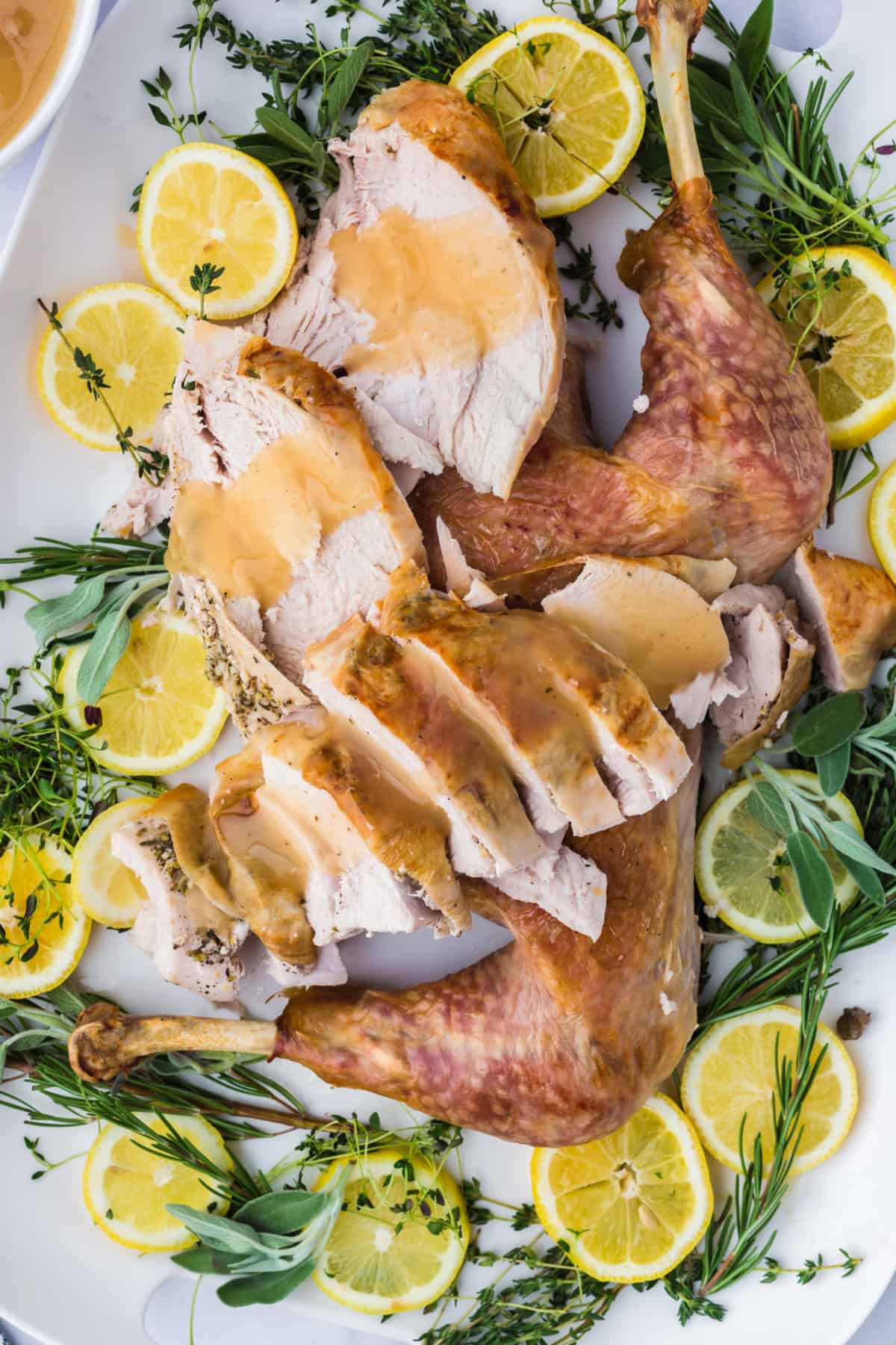 sliced roasted spatchcock turkey on a plate with gravy on it, with a fork.