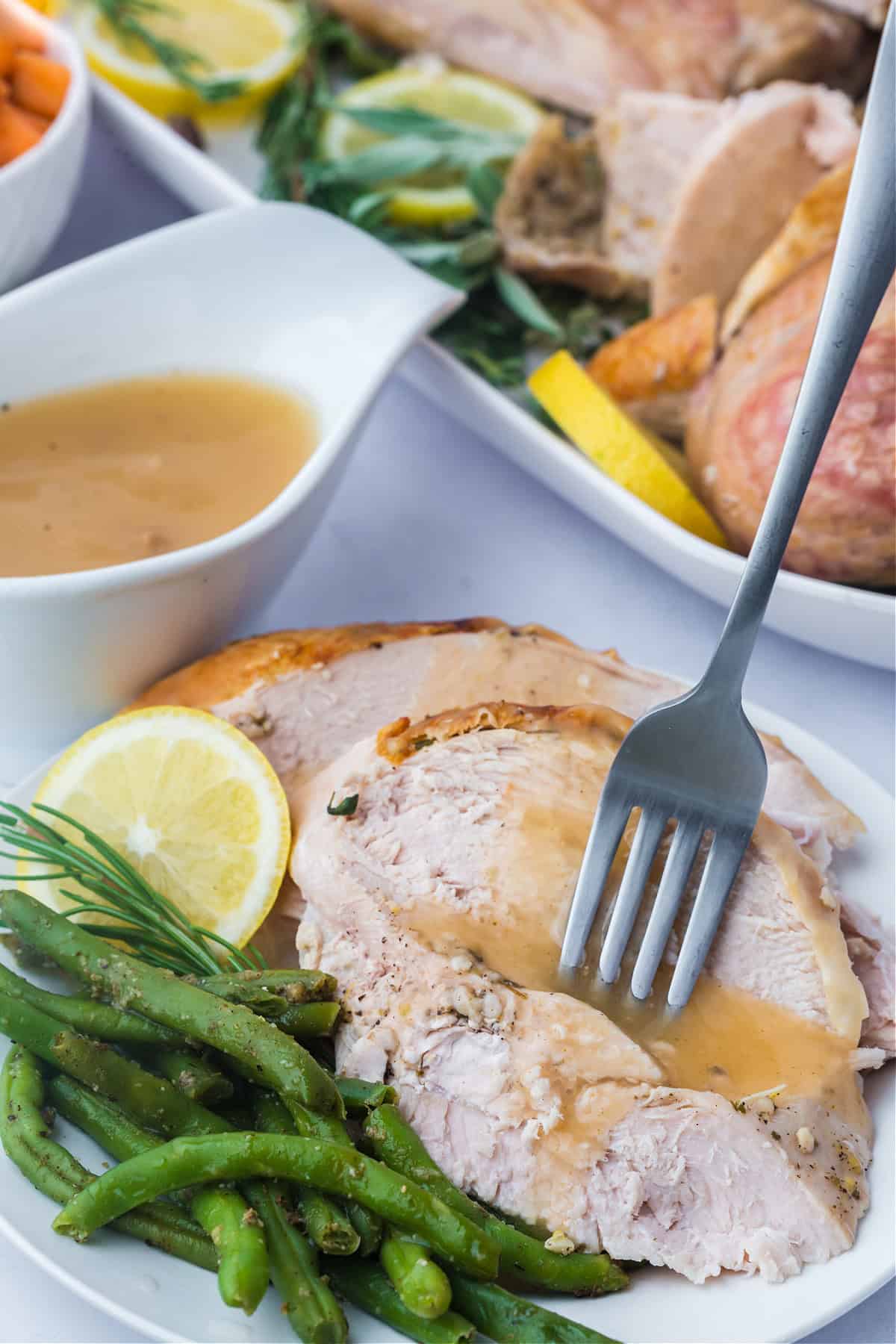 sliced roasted spatchcock turkey on a plate with green beans and a side of gravy.