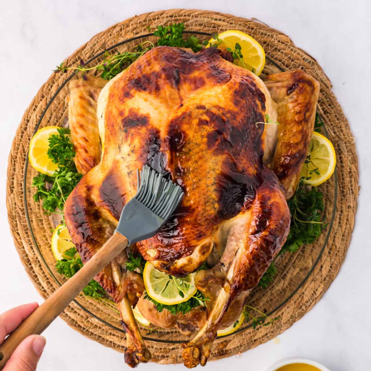 basting a whole cooked honey glazed turkey.