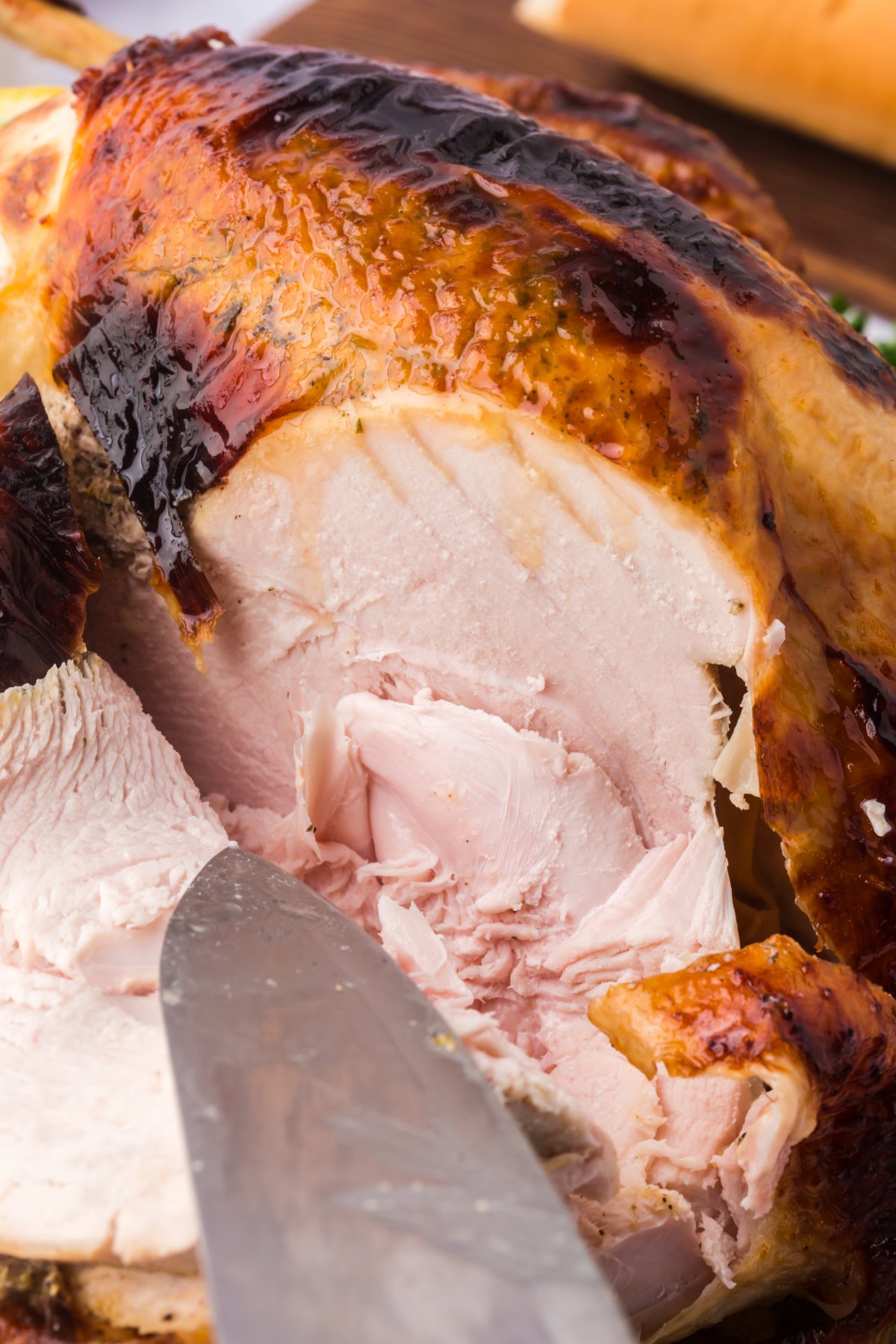 slicing a whole cooked honey glazed turkey with a knife.