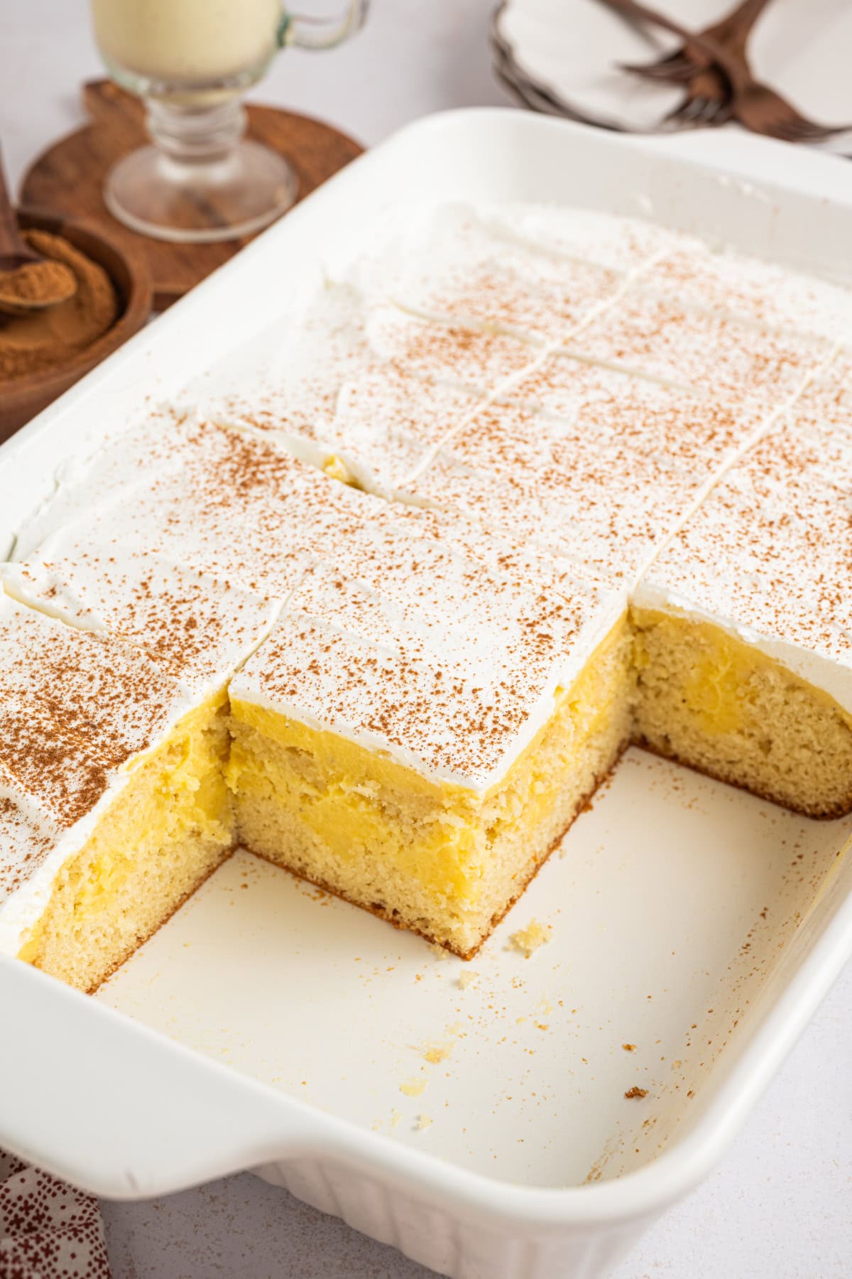 sliced eggnog poke cake in a white baking dish with pieces taken out.