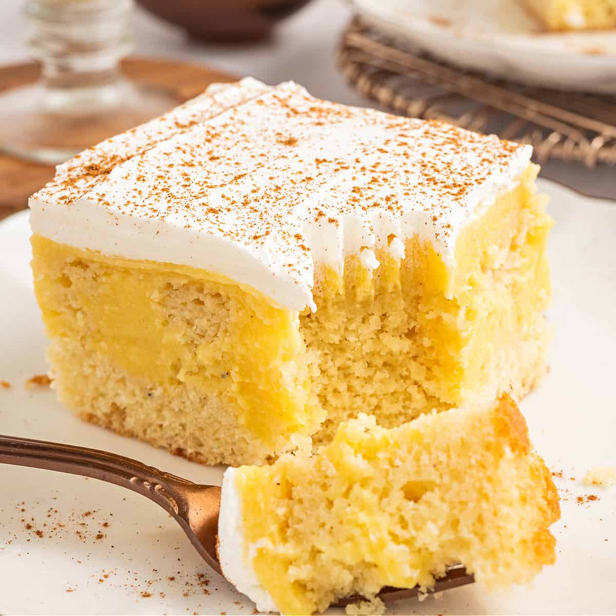 a slice of eggnog poke cake with whipped topping and cinnamon on top.