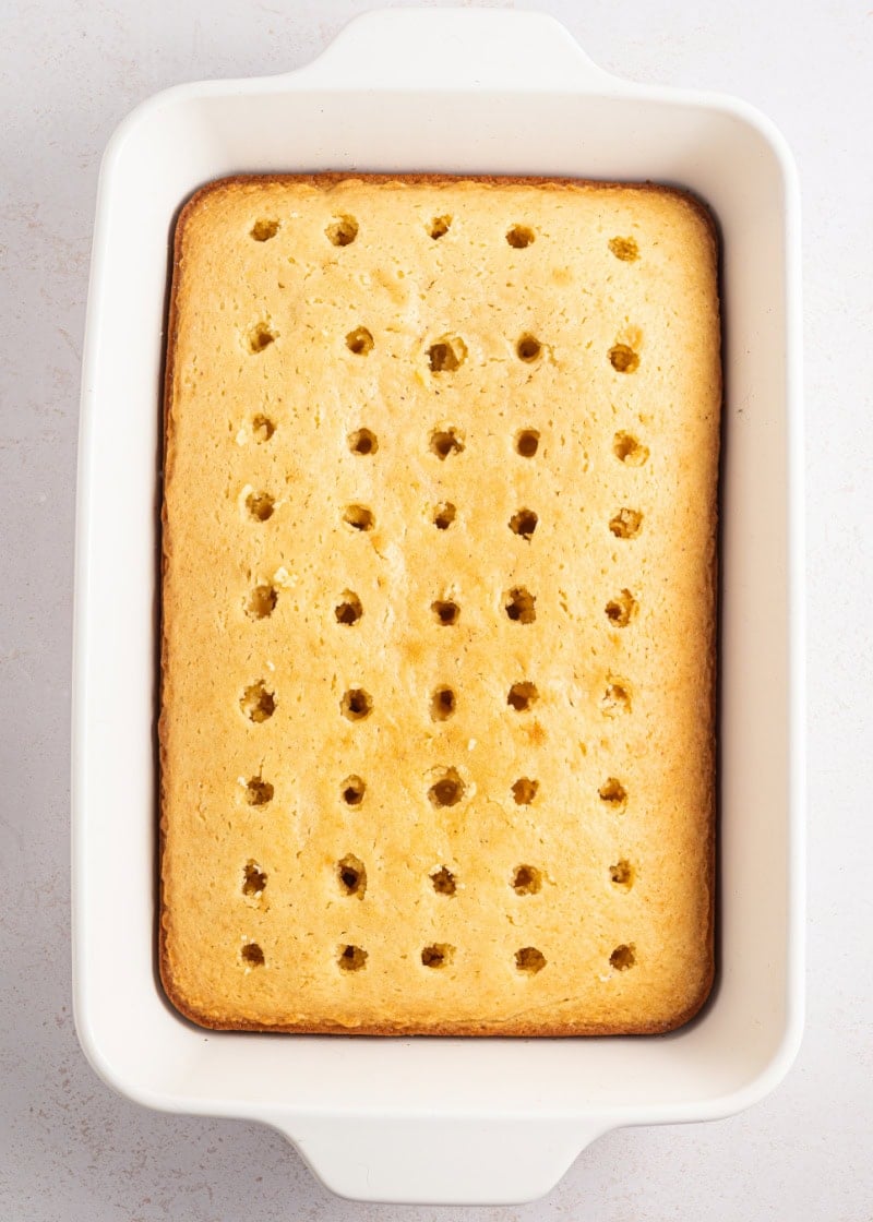 baked cake in a white baking dish with holes poked into it.