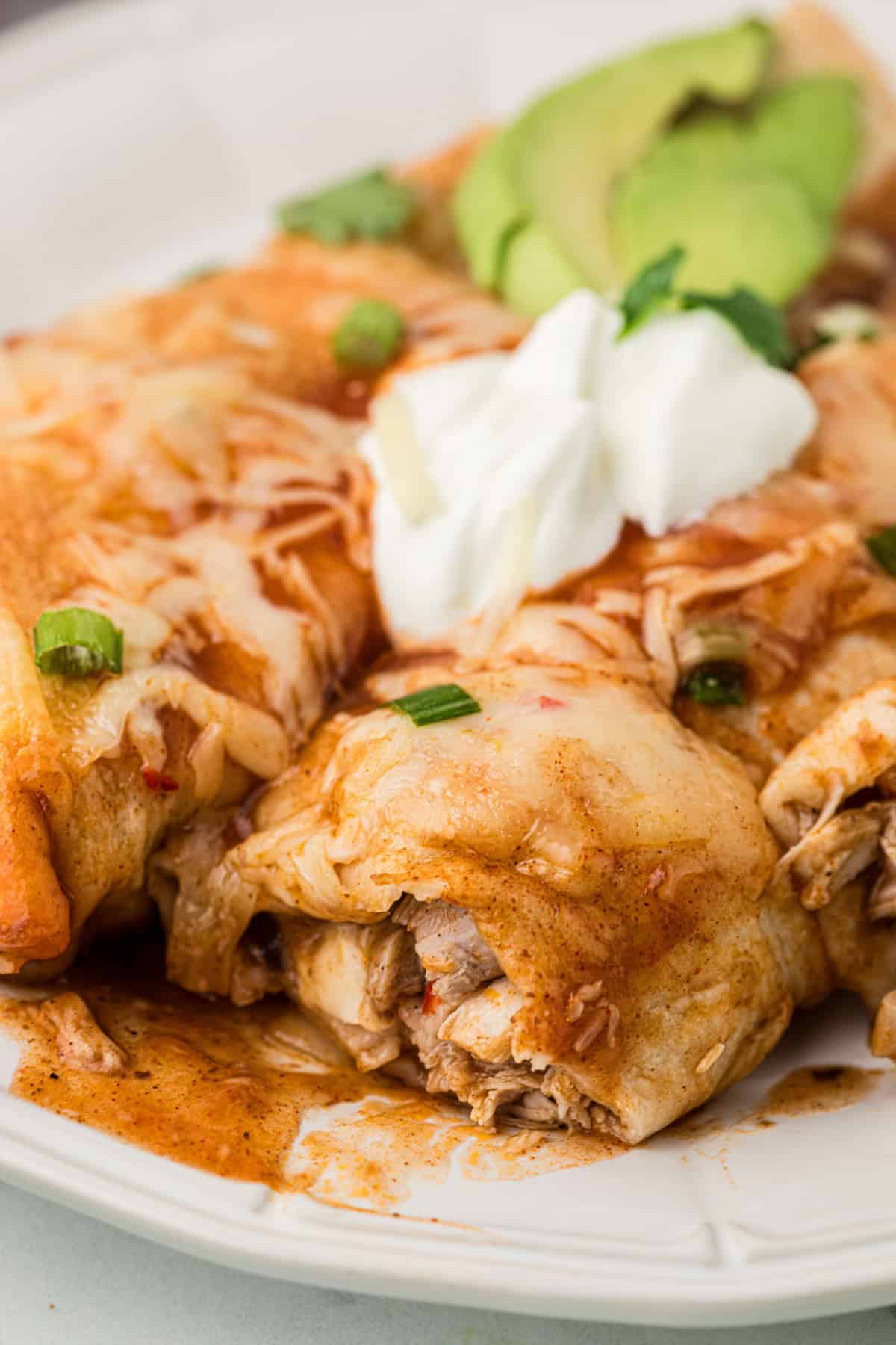 Closeup of Turkey Enchiladas on a plate with sour cream on top.
