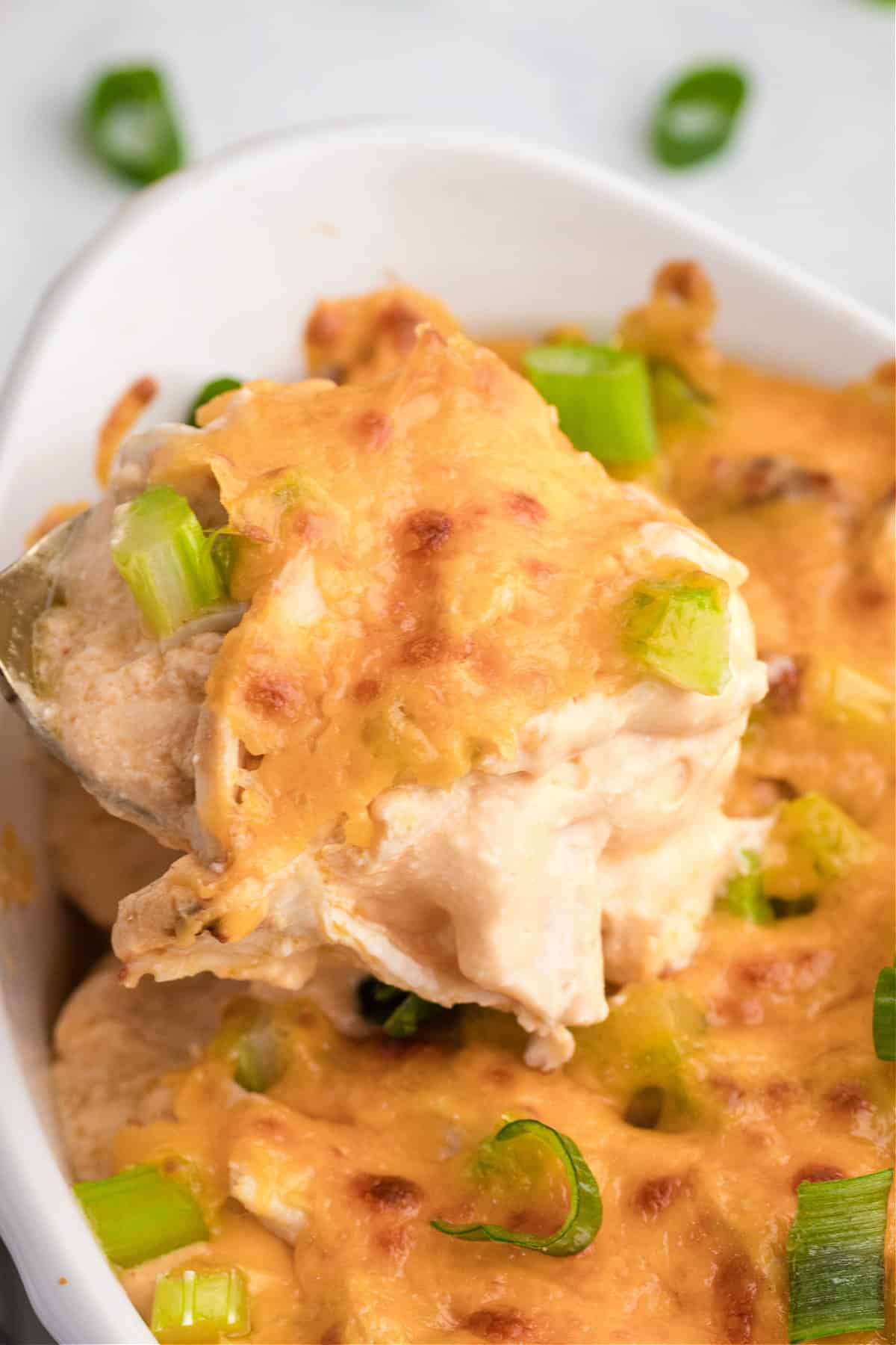 a spoon taking some buffalo chicken dip with cottage cheese out of a dish.