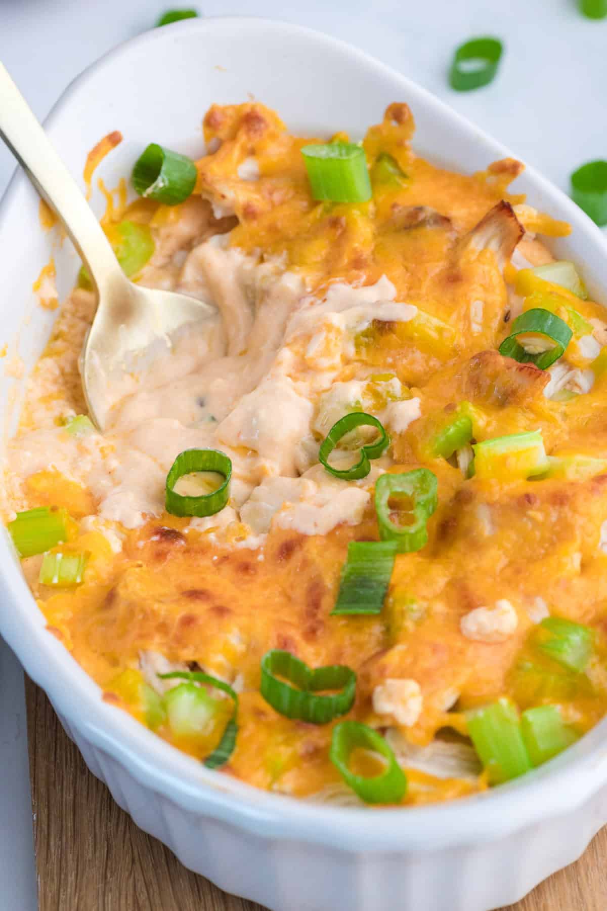 baked cottage cheese buffalo chicken dip in a white dish with a spoon in it.