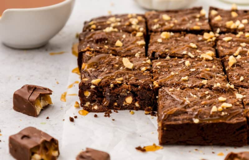 Snickers Brownies with caramel sauce drizzled on top.