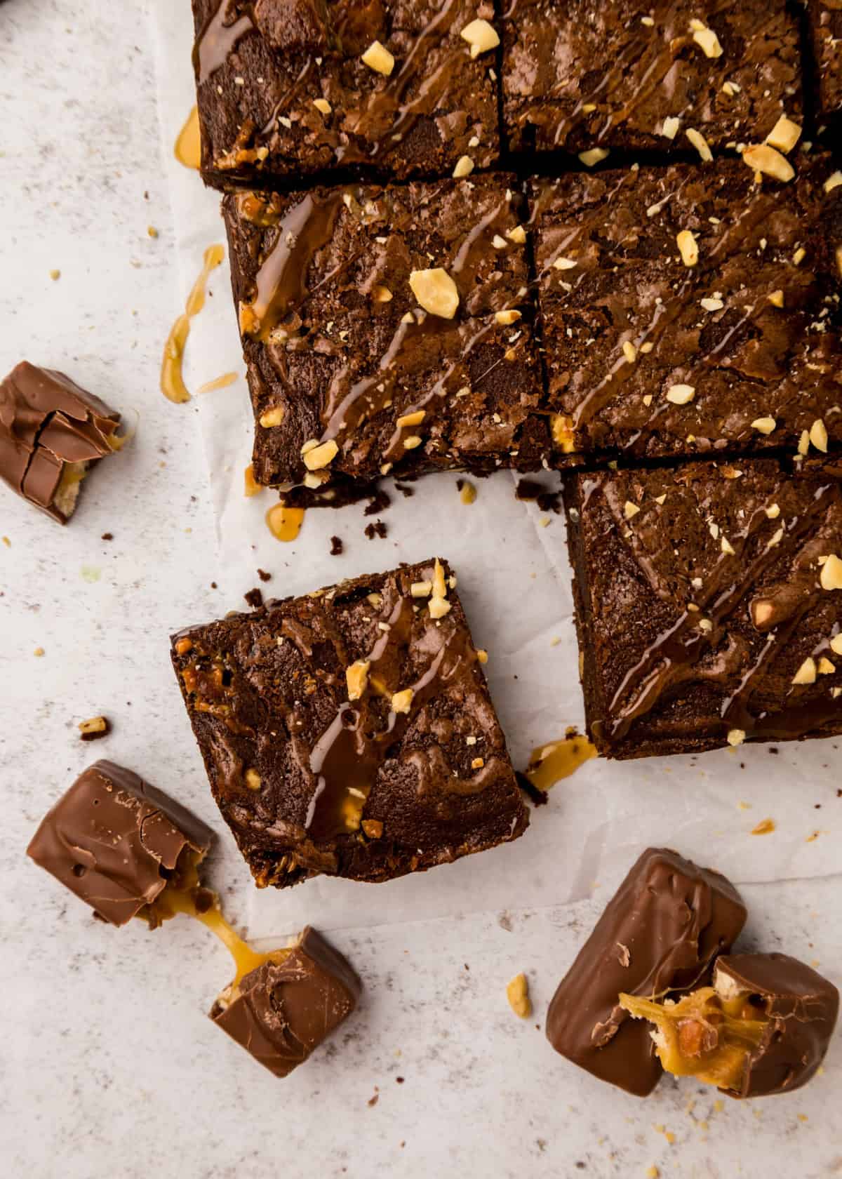 Snickers Brownies with caramel sauce drizzled on top.