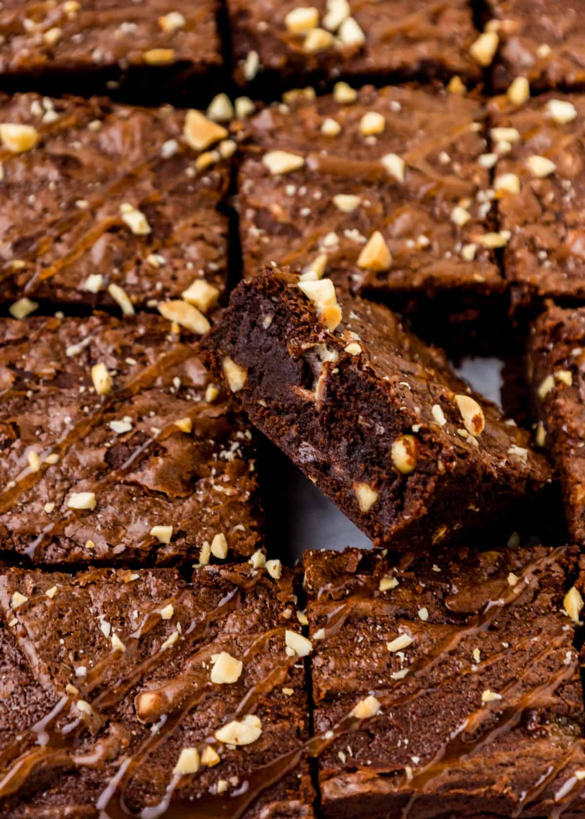 Snickers Brownies in a pan with caramel sauce drizzled on top.