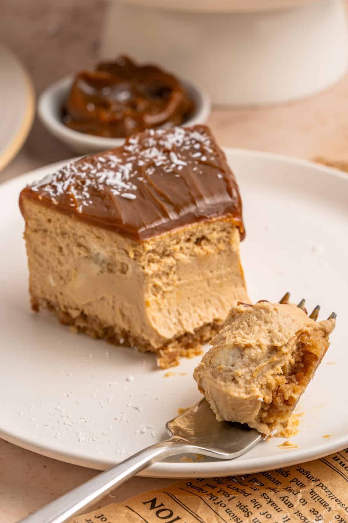 A slice of Dulce de Leche Cheesecake and a fork on a plate.