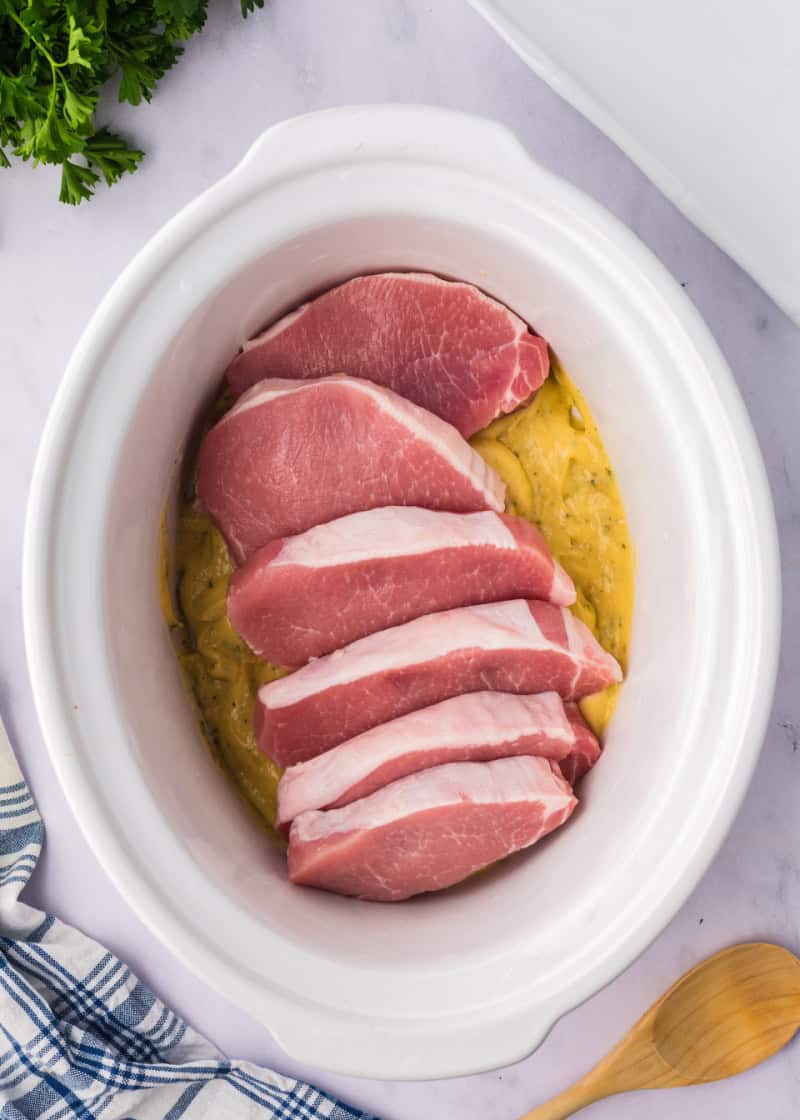 sauce in a crockpot with pork chops on top.