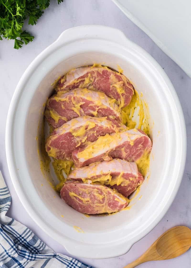 pork chops and sauce in a crockpot ready to be cooked.