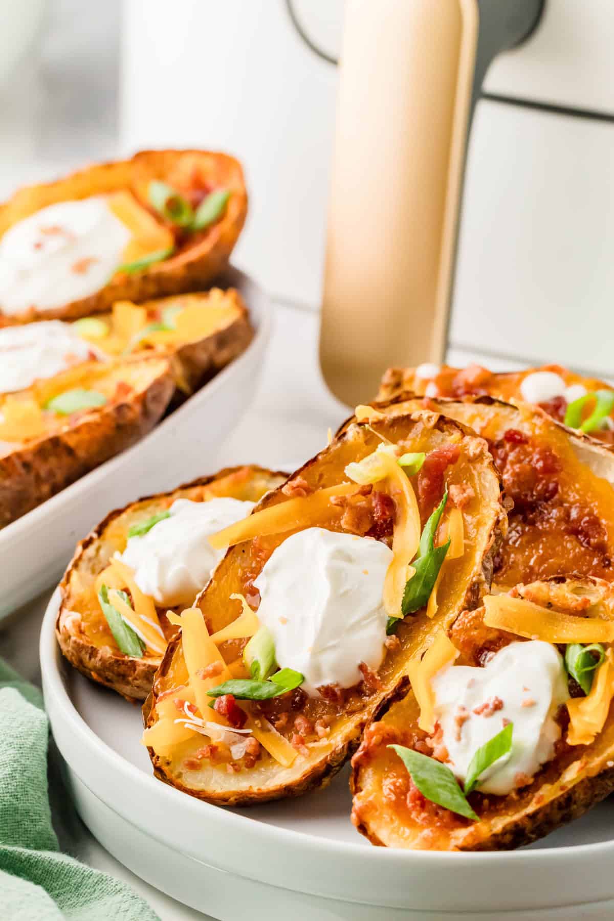Air Fryer Potato Skins stacked on a white plate.