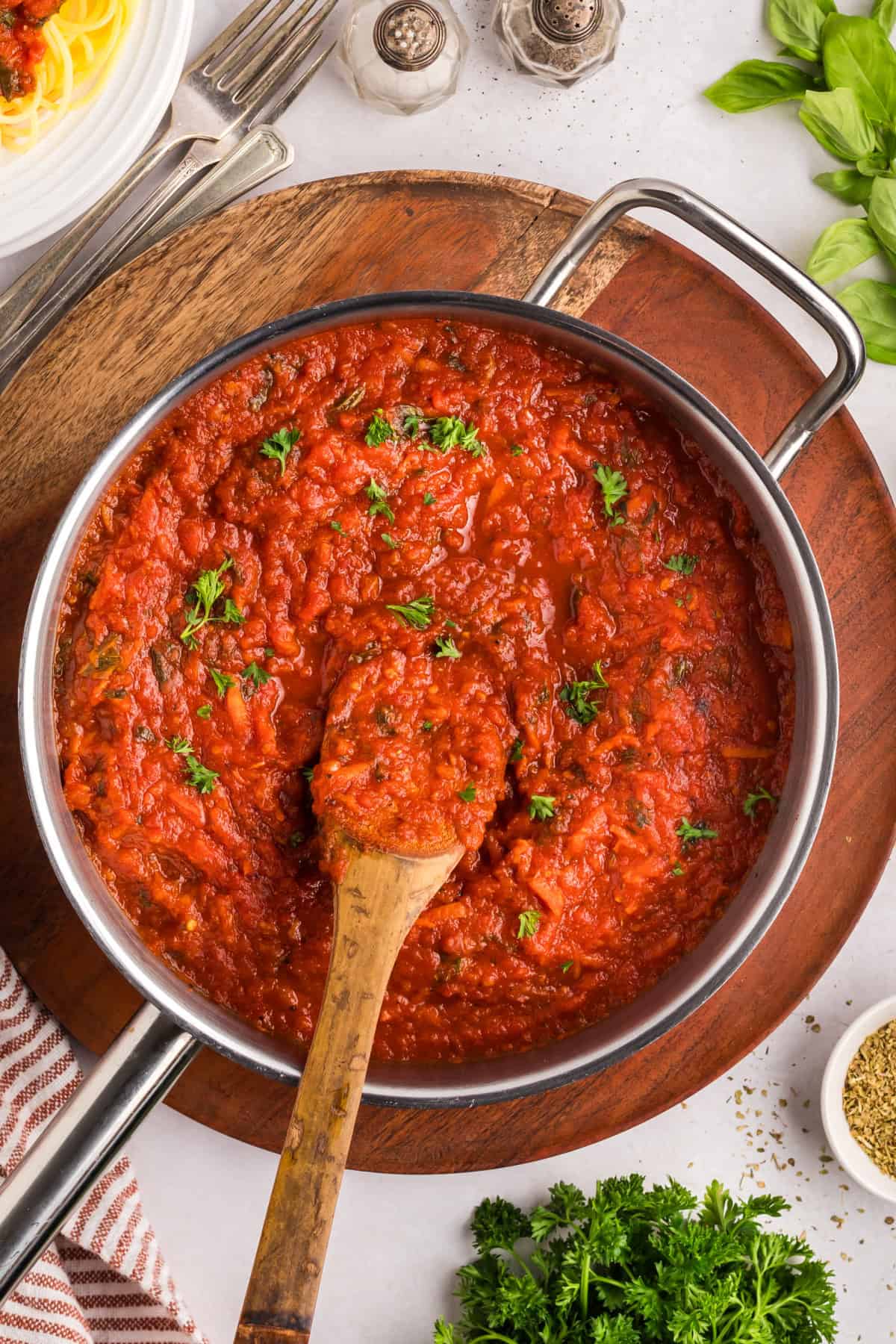 A wooden spoon stirring homemade spaghetti sauce in a large pot.