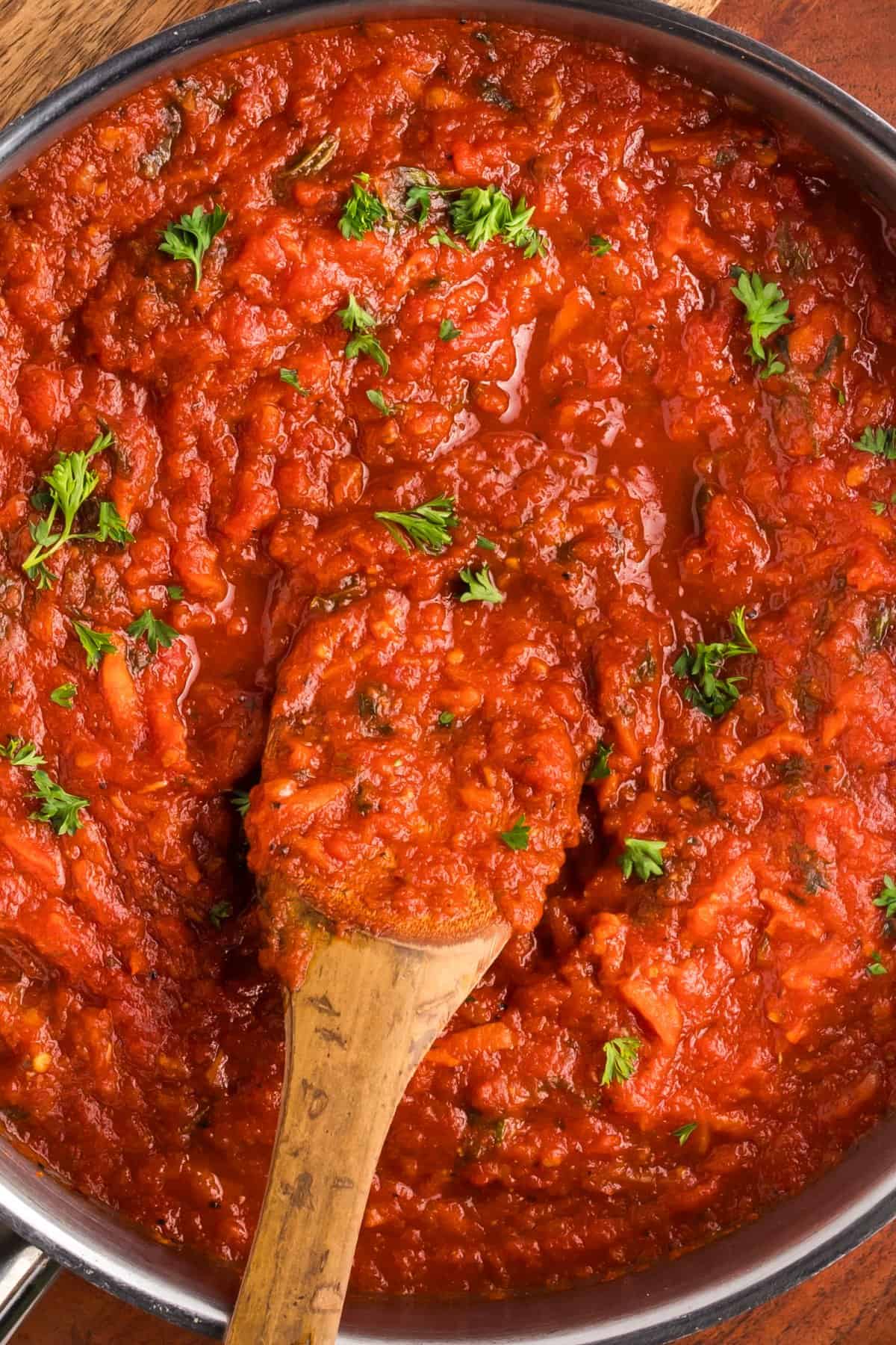 Homemade pasta sauce in a large pot with a wooden spoon.