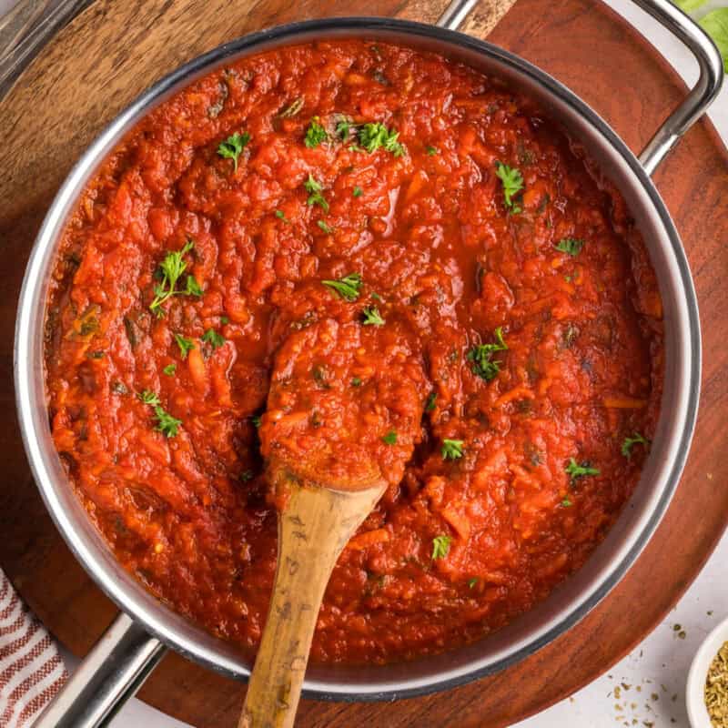 Homemade spaghetti sauce in a large pot with a wooden spoon.