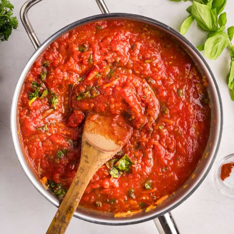 Homemade pasta sauce in a large pot with a wooden spoon.
