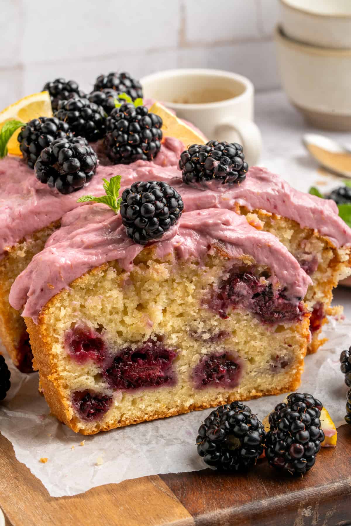 Slices of Blackberry Lemon Loaf on a table with fresh blackberries.