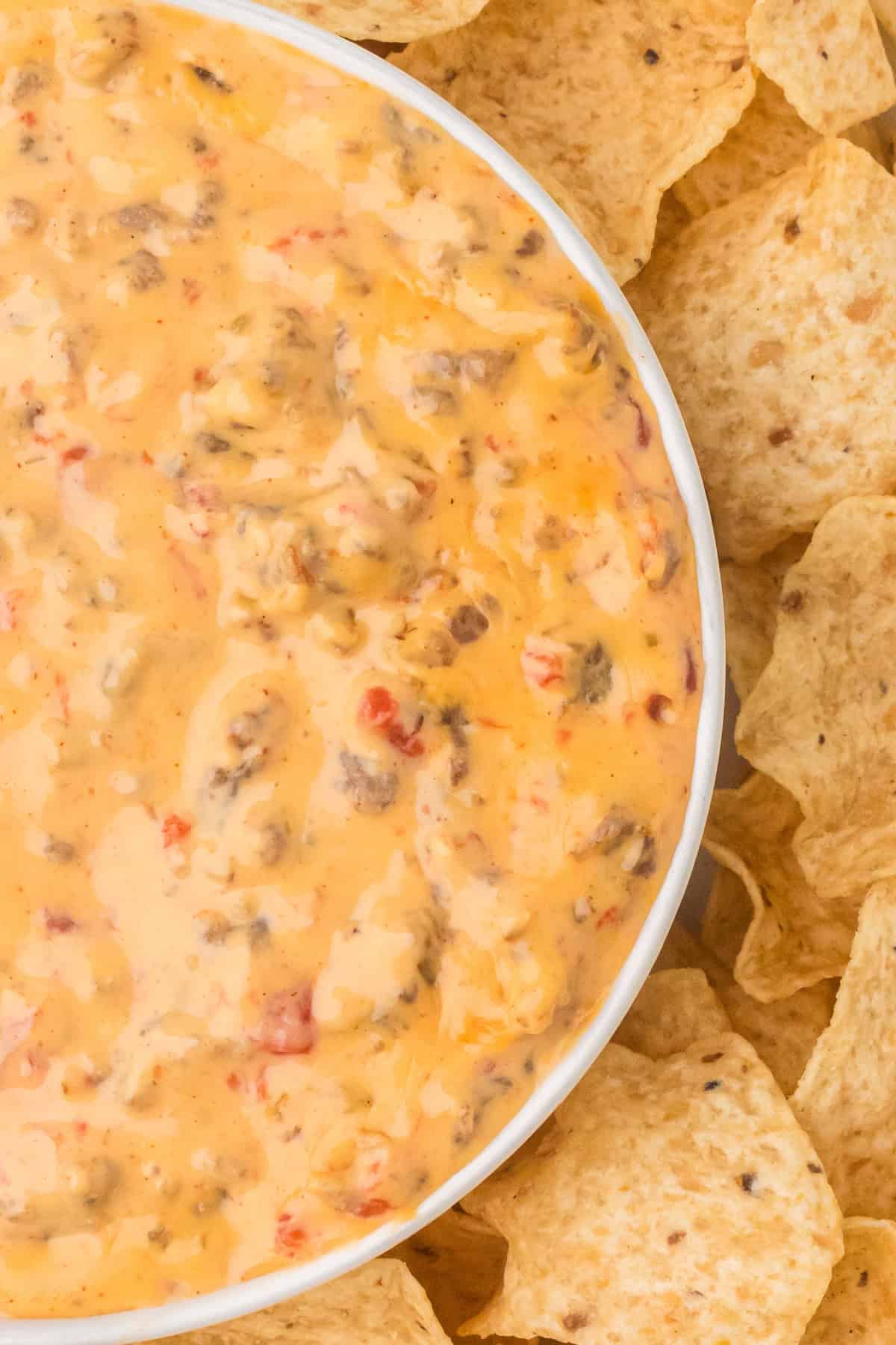 Rotel Dip in a white bowl with tortilla chips beside it.