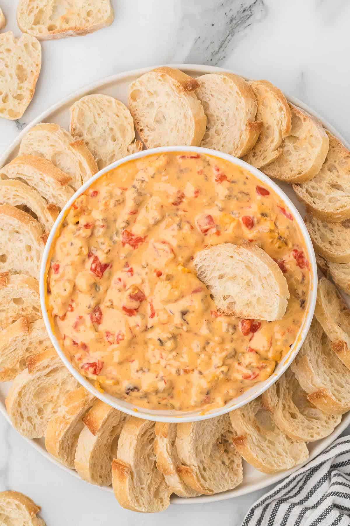 Rotel Dip in a white bowl with sliced baguette.