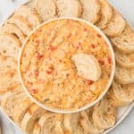 Rotel Cheese Dip with sausage in a white bowl with baguette slices.