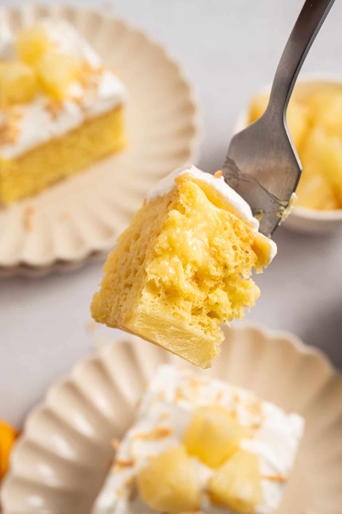 Pineapple Poke Cake with pudding inside the cake on a fork.