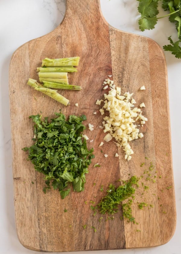 fresh lemongrass, cilantro and garlic on a cutting board.
