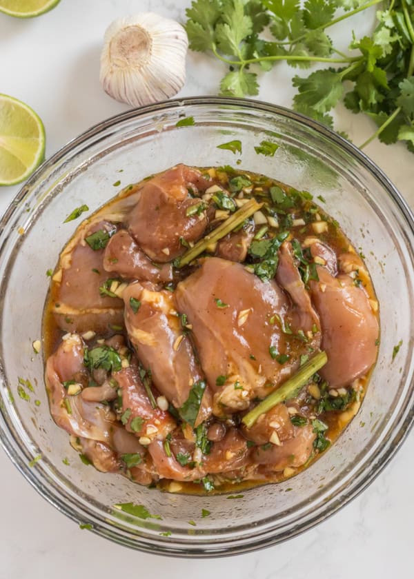 chicken thighs in a thai sauce marinating in a glass bowl.