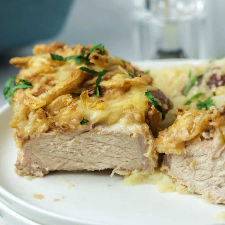 A cut open french onion pork chop on a plate.