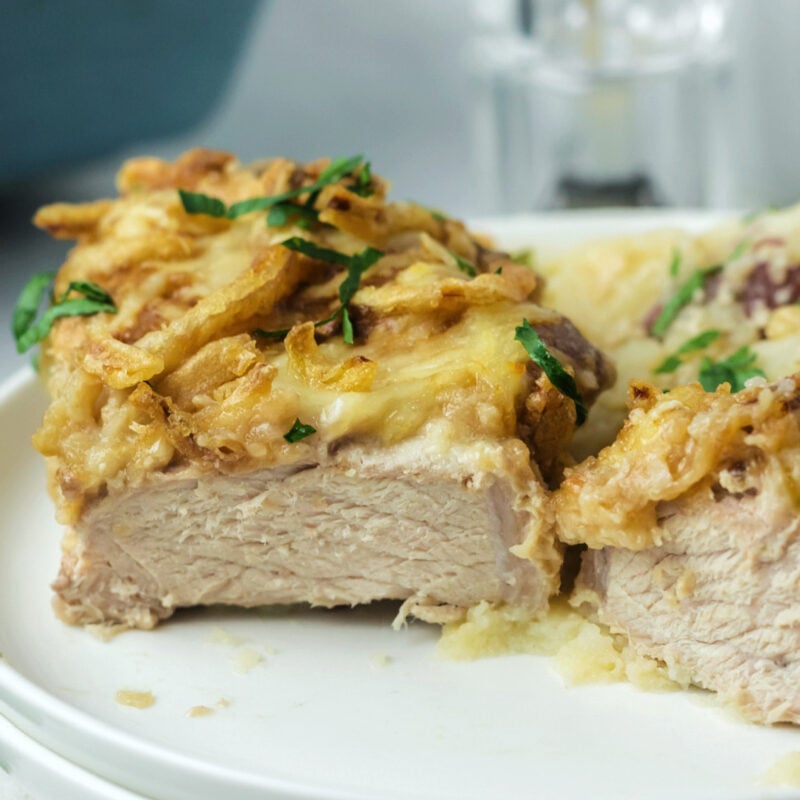 A cut open french onion pork chop on a plate.