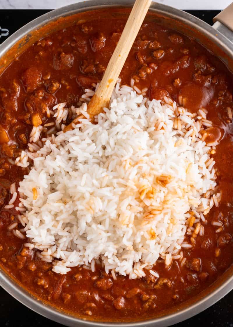 cooked rice added to cooked tomato sauce and ground beef mixture.