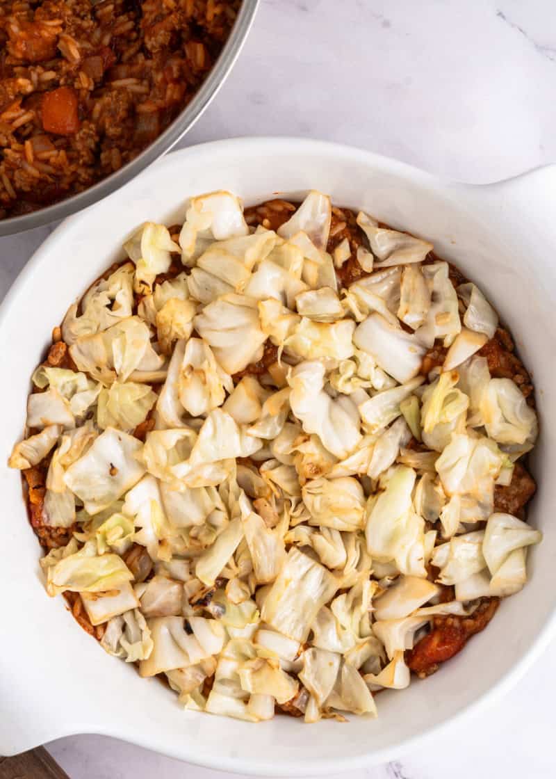 assembling layers of stuffed cabbage casserole in a dish.