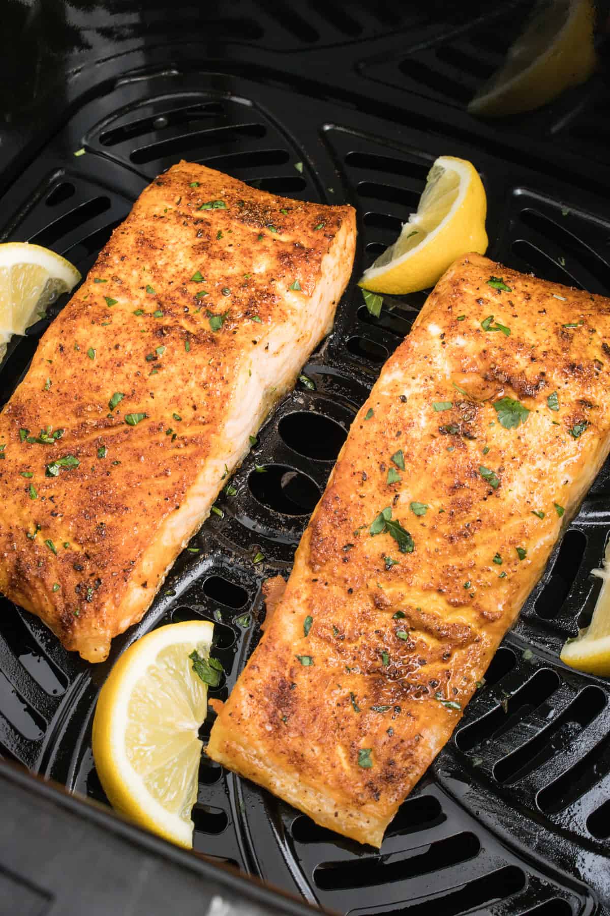 Salmon cooking in an air fryer basket.
