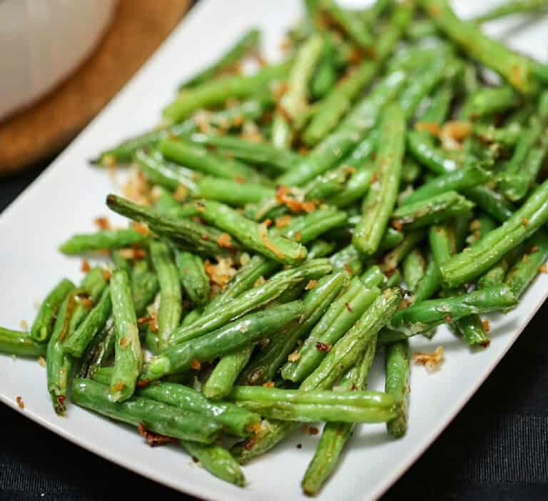 a white plate with crispy parmesan green beans.