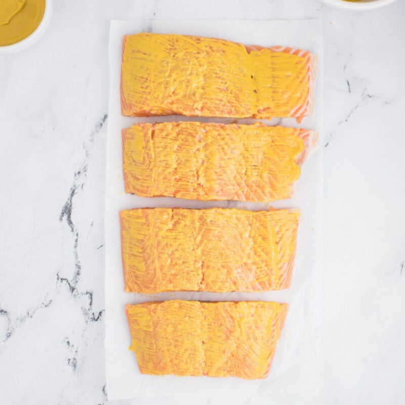 Glaze on uncooked salmon fillets on a table.