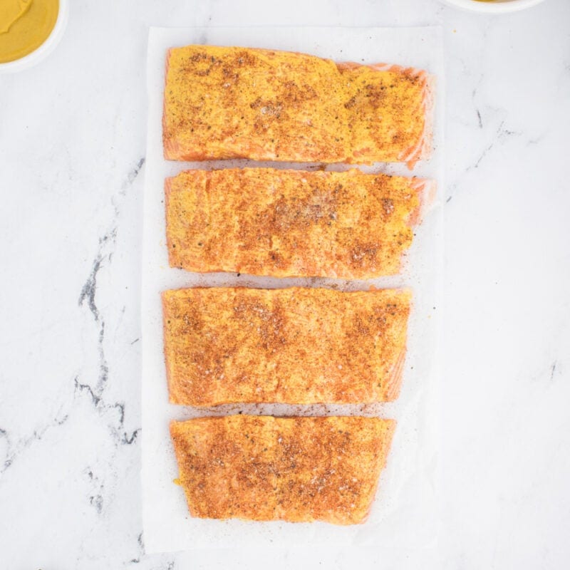 Seasoned glazed salmon fillets on a table.