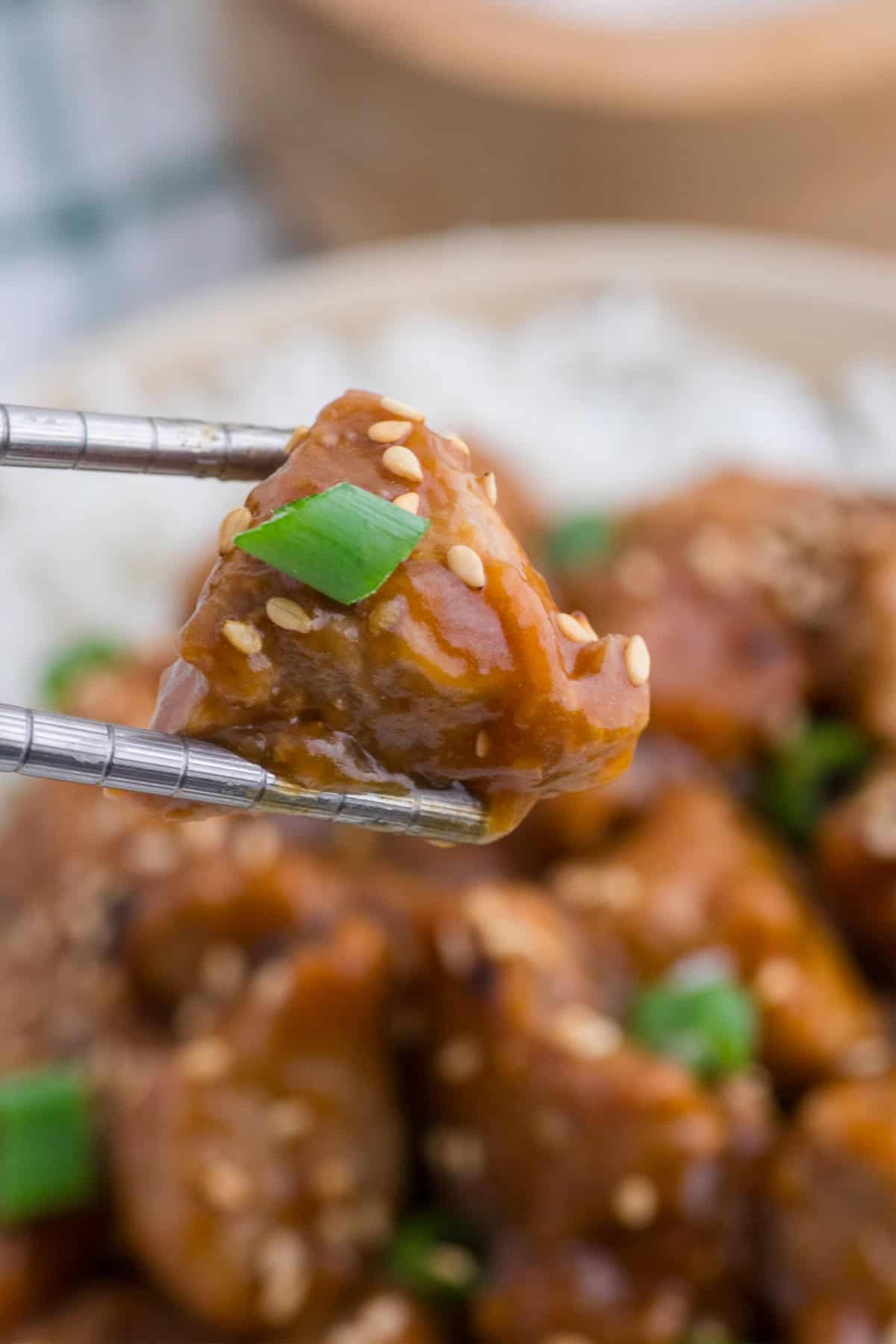 Chopsticks picking up a piece of asian pork tenderloin.