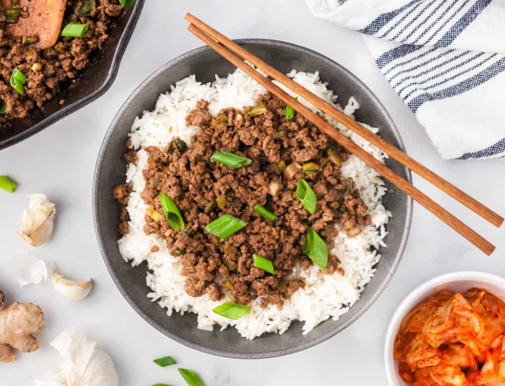 Korean ground beef in a bowl over rice and topped with green onions.