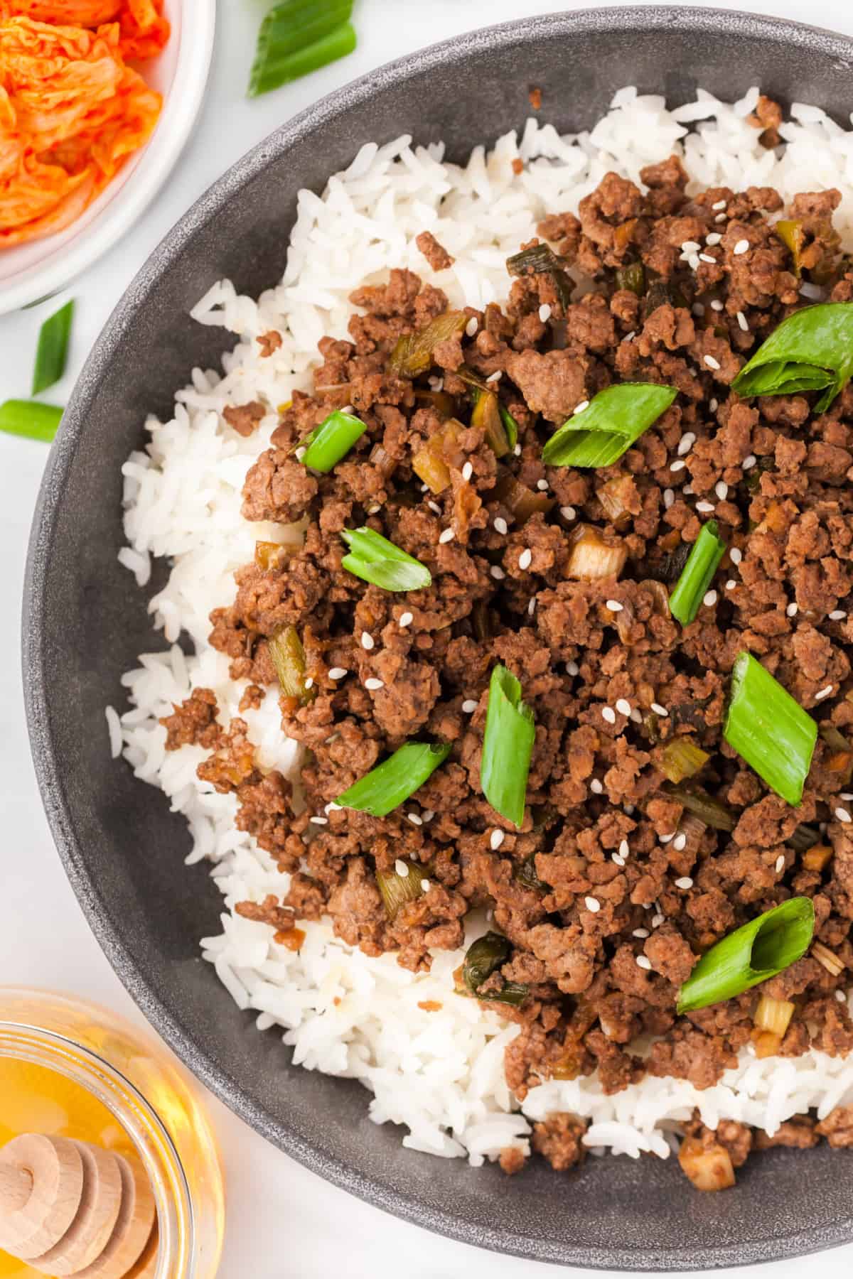 Korean ground beef in a bowl over rice and topped with green onions and sesame seeds.