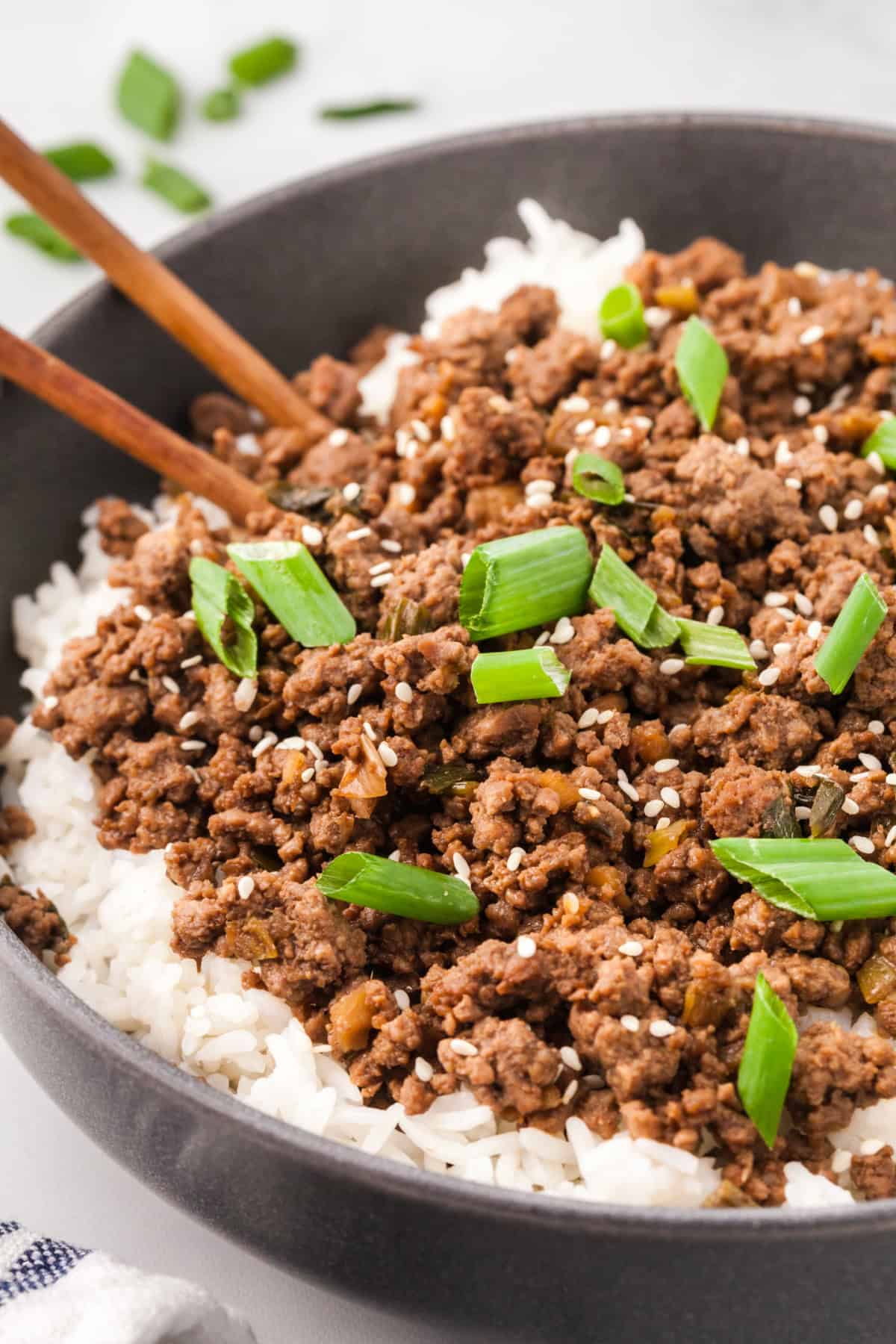 Korean ground beef in a bowl over rice and topped with green onions and sesame seeds.